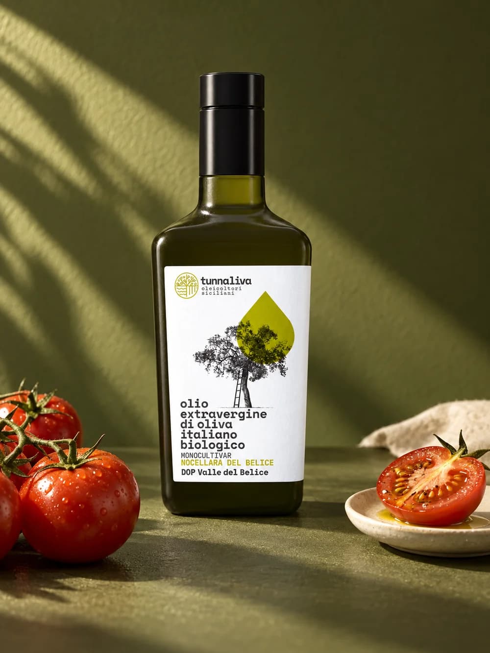 Bottiglia di olio su fondo verde oliva con pomodori freschi