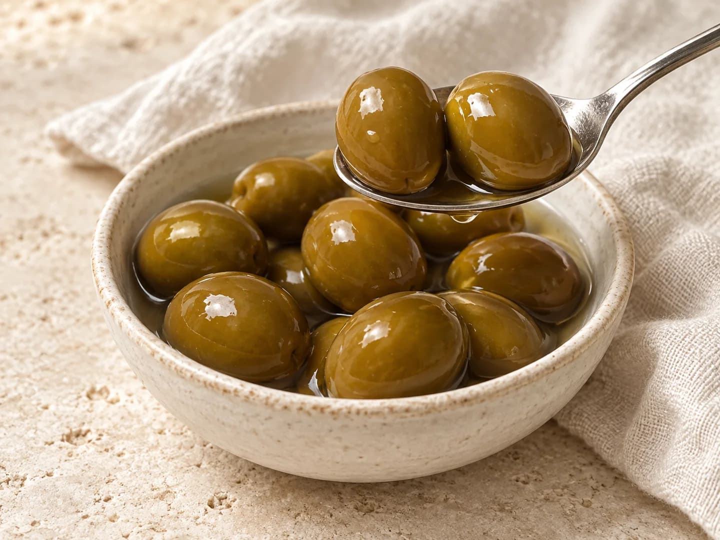 Olives vertes entières en saumure dans un bol en céramique