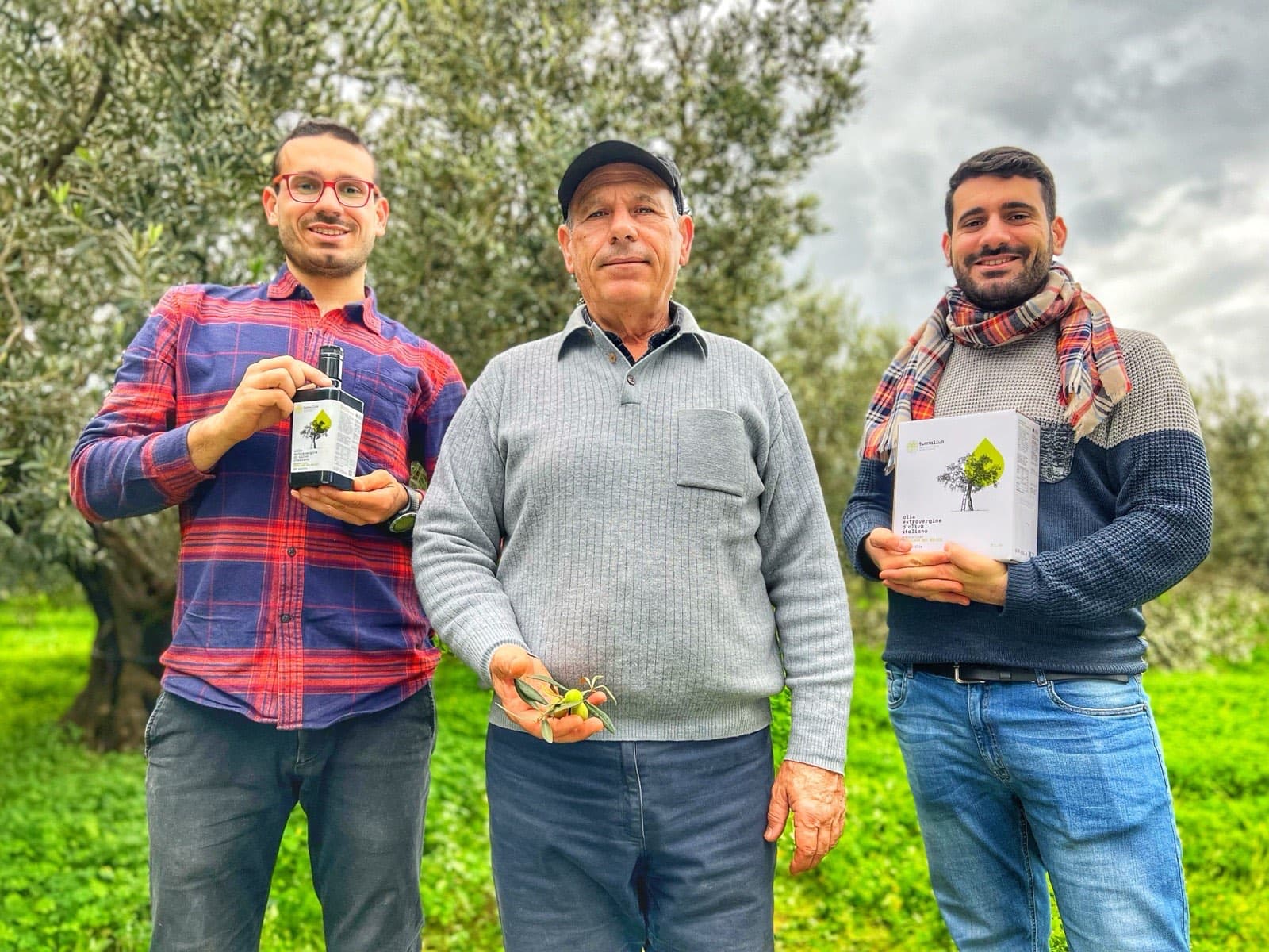 La famiglia in uliveto con una bottiglia e una confezione del proprio olio