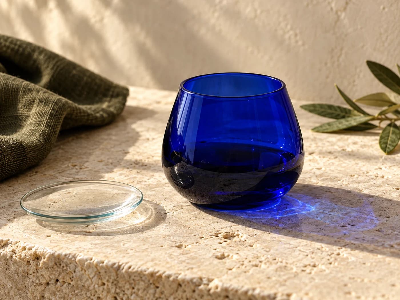 Bicchiere blu da degustazione dell’olio con il suo coperchio su un piano in pietra