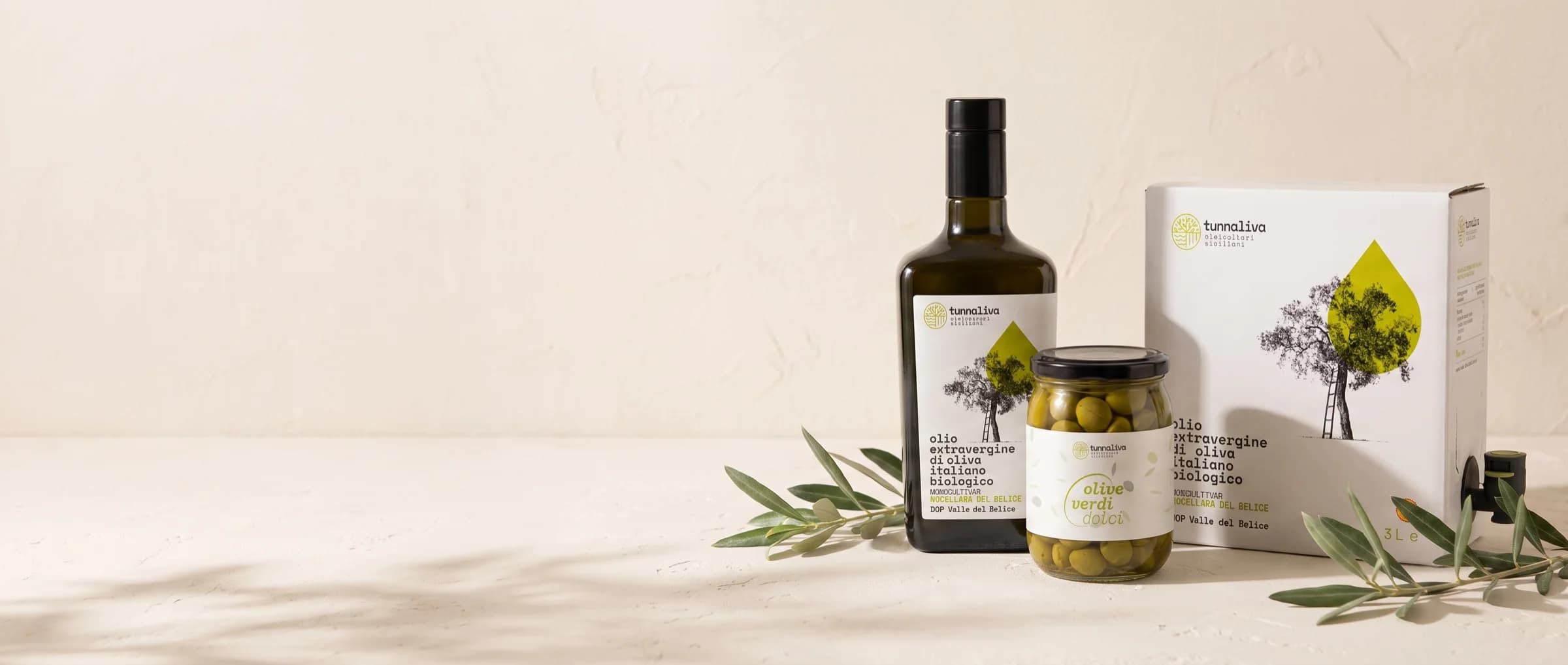Les formats d'huile et les olives en bocal sur un plan clair, avec des rameaux d'olivier