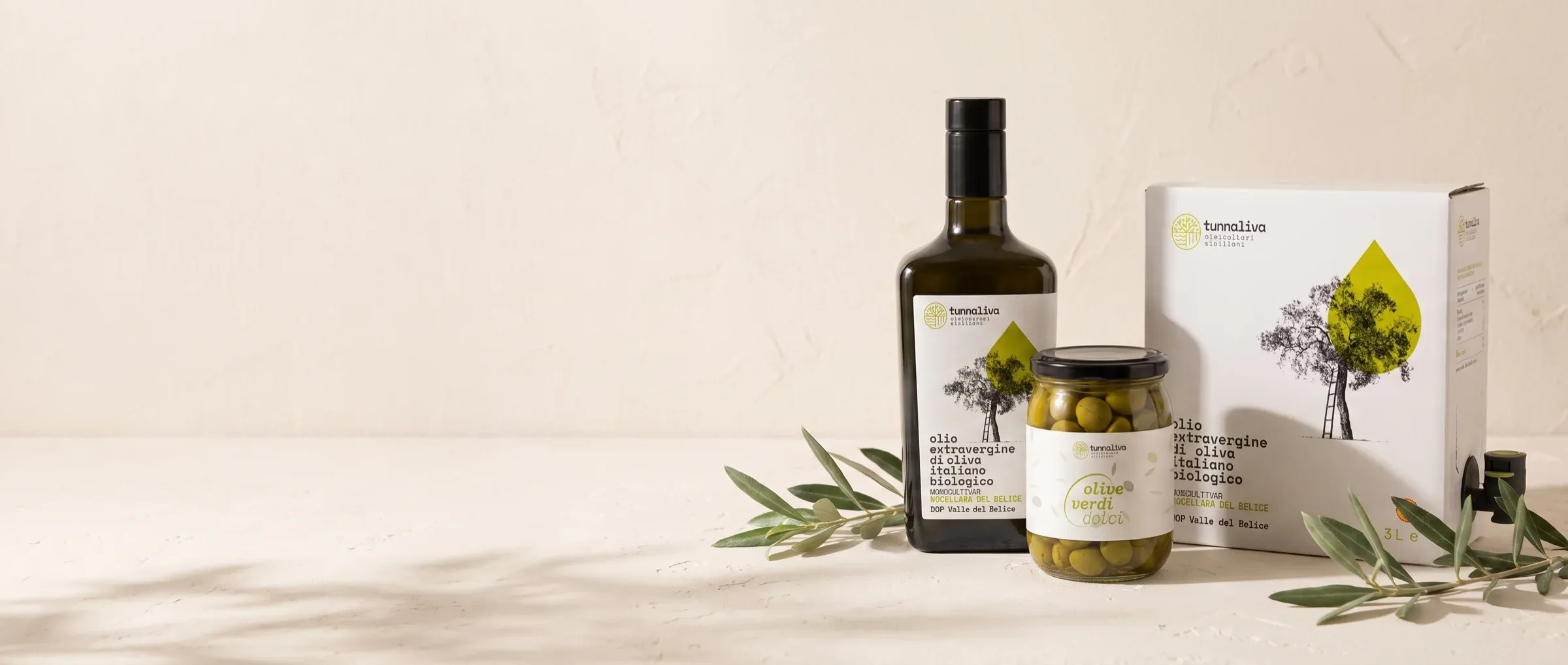 I formati dell'olio e le olive in barattolo su un piano chiaro, con rametti d'olivo accanto